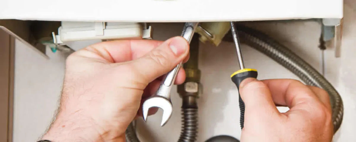 Boiler repair technician tightening pipe fittings and connections in Orange, CA