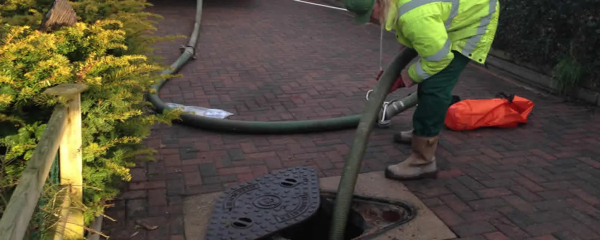 Septic tank cleaning technician servicing a septic tank with a vacuum hose in Orange, CA